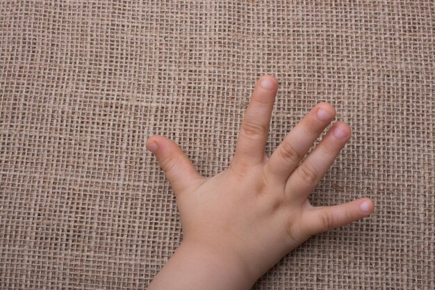 Foto mano del bambino con sfondo di tela di lino