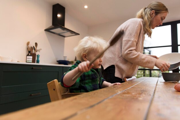 A toddler helping to bake a cake holding a large spatula