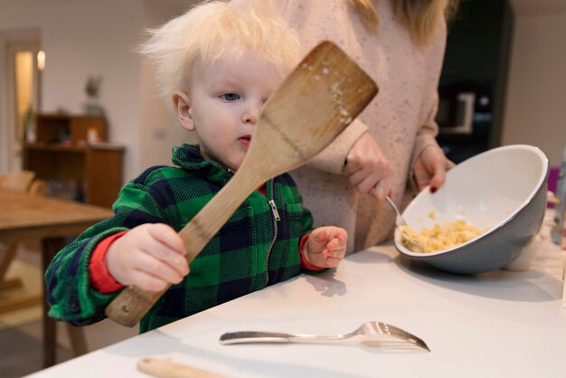 A toddler helping to bake a cake holding a large spatula