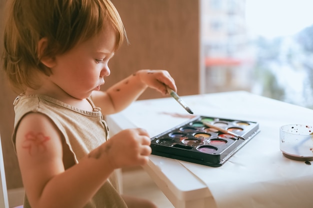 Toddler at home draws paints on himself closeup