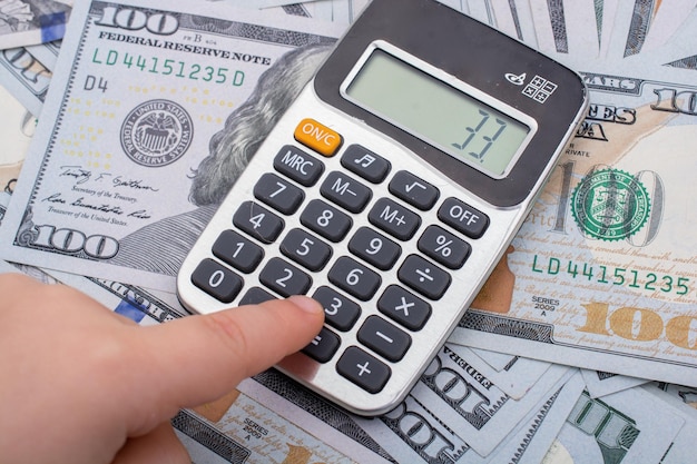 Toddler is holding calculator on the US dollars banknotes