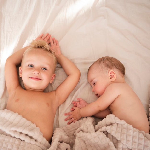 Photo toddler laying next to baby