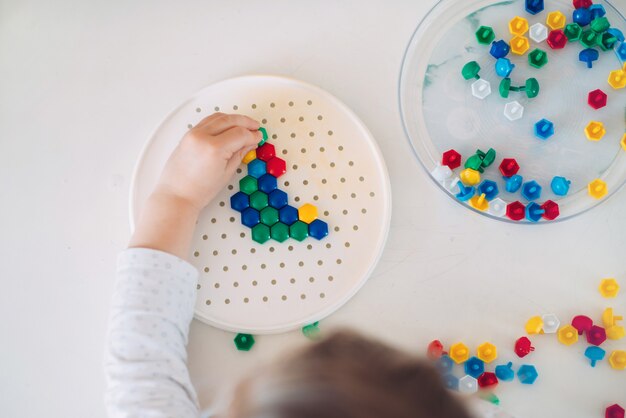 Toddler playing mosaic on the table at home.