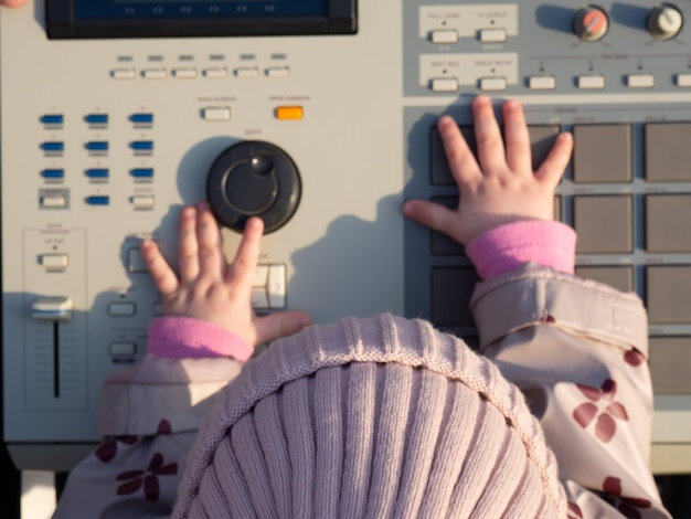 幼児が電子楽器のボタンを押して、ヒップホップ楽器を作成するためのドラムマシン