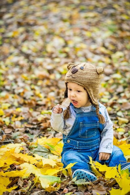 toddler sitting in the park in autumn leaves