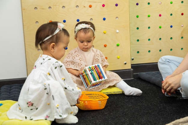 Photo toddler twin girls playing toys in the kindergarten