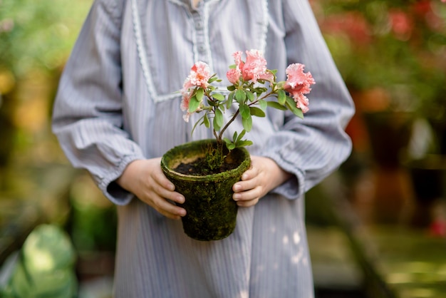 フラワーバスケットを持つ幼児。ピンクの花を保持している女の子