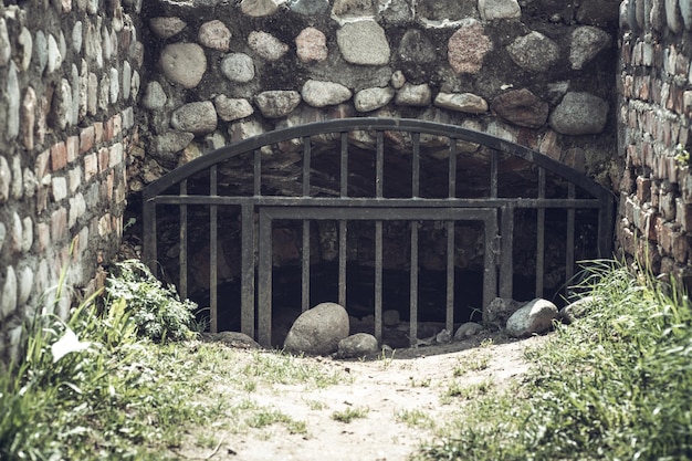 Toegang tot een geheime verlaten betonnen ondergrondse bunker uit de tijd van de USSR. De ingang wordt afgesloten door een sterke metalen grill