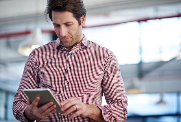 Toekomstige technologie in het hedendaagse bedrijf Bijgesneden afbeelding van een volwassen man die zijn digitale tablet gebruikt in een industriële kantoorruimte