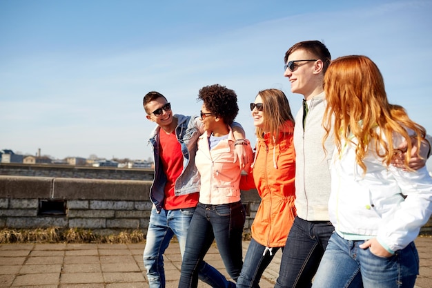 toerisme, reizen, mensen en vrije tijd concept - groep gelukkige tienervrienden die langs de stadsstraat lopen en praten