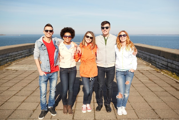 toerisme, reizen, mensen en vrije tijd concept - groep gelukkige tienervrienden in zonnebril knuffelen op straat in de stad