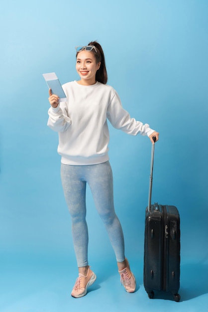 Toerisme zomervakantie en vakantie concept Gelukkige vrouw in casual kleding met reistas en vliegticket over blauwe achtergrond
