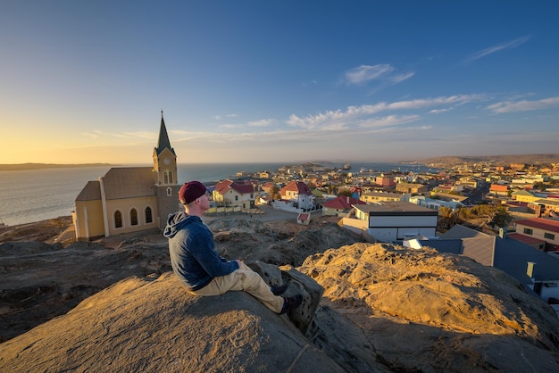 Toerist bovenop een heuvel geniet van het uitzicht op luderitz in Namibië bij zonsondergang