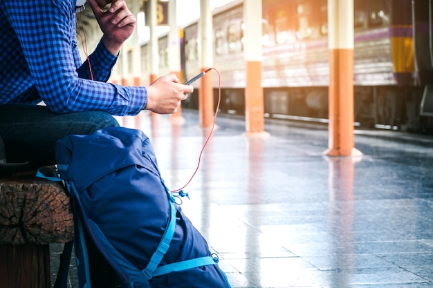 Toerist die backpacker mobiele telefoon met behulp van om bij station te reizen