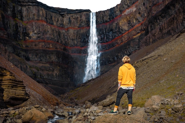 Toerist die de hengifoss-waterval in IJsland bekijkt
