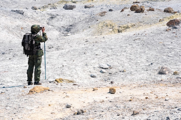 Toerist die foto's maakt van het Solfatara-veld op de helling van het eiland Mendelejev, vulkaan Kunashir