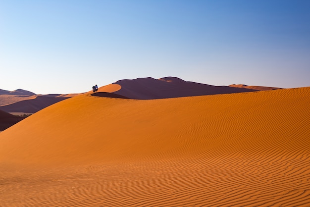 Toerist die op de zandduinen in Sossusvlei, Namib-woestijn, het Nationale Park van Namib Naukluft, Namibië lopen.