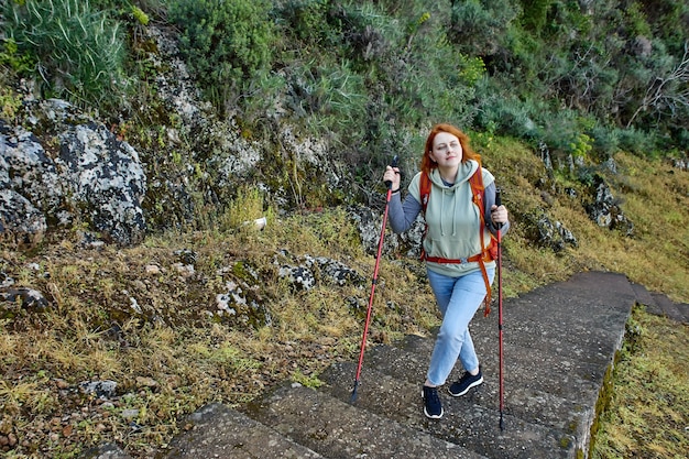 Toerist die rond fethiye loopt in turkije, jonge europese vrouw klimt trappen naar amyntas-rotsgraven met behulp van wandelstokken