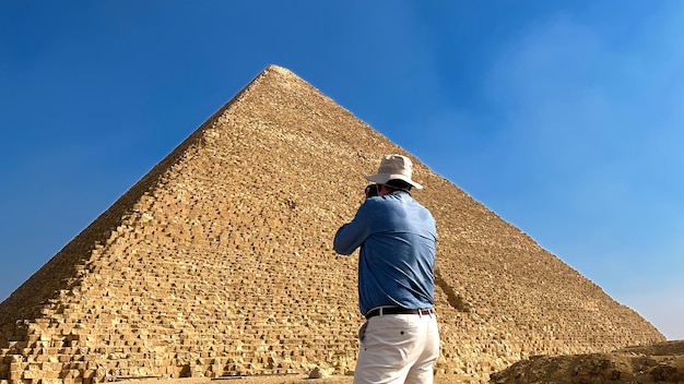 Toerist met een hoed die een piramide in Egypte fotografeert