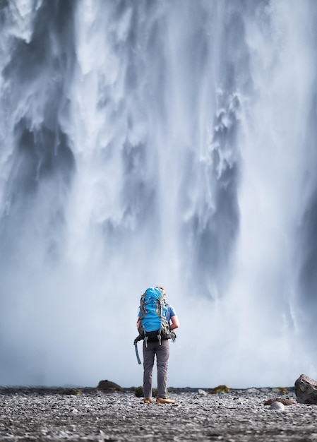 Toerist met rugzak op de achtergrond van de Skogafoss-waterval Reizen op IJsland Toerist in de beroemde plaats in IJsland Reisbeeld