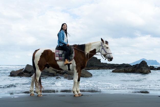 Toeriste vrouw rijdt op een paard naast het strand