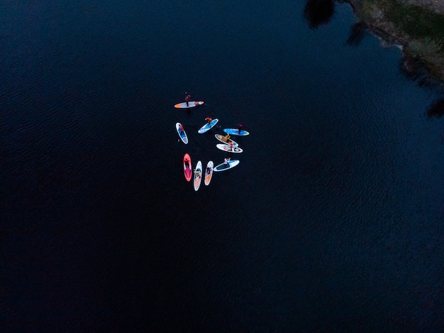 Toeristen drijvend op sup board in blauwe zee. bovenaanzicht van een groep mensen op sup-boards drijvend in een rustige, heldere zee