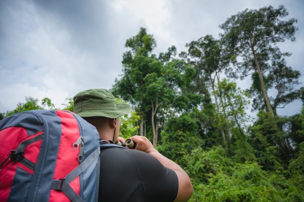 Toeristen kijken naar de neushoornvogel en de aap met een verrekijker in het tropische woud. Khao Yai Nationaal Park, Thailand. Vogel-, neushoornvogel- en apensafari. Afbeelding van het concept van ecotoerisme.