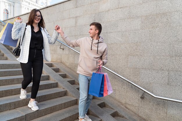 Toeristen lopen door de stad met aankopen en souvenirs in hun handen Guy helpt meisje de trap af te gaan