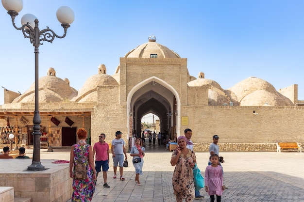 Toeristen lopen in de oude stad bij de ingang van het overdekte kruispunt en de souvenirmarkt Bukhara, Oezbekistan