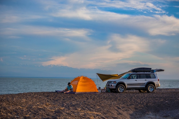 Toeristen met de auto met een tent aan de oever van het meer