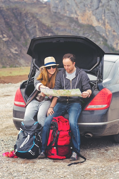 Toeristen met een kaart en rugzakken in de auto in de bergen