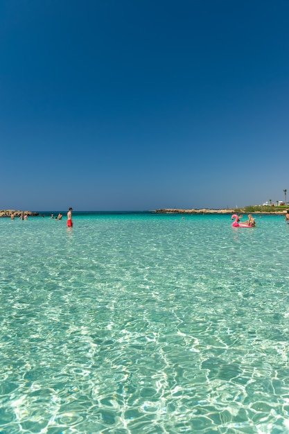 Toeristen ontspannen en zwemmen op een van de populairste stranden van het eiland.