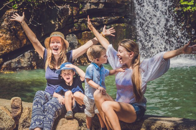 Toeristen vrouwen en kinderen tegen de waterval met hun handen omhoog