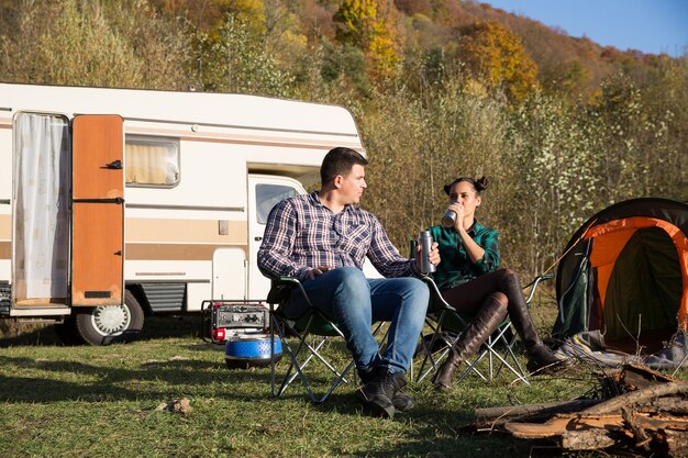 Toeristenpaar die samen in wildnerss van de bergen ontspannen. paar kamperen met retro kampeerauto.