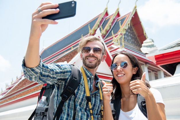 Toeristenpaar die selfie bij Thaise tempel op vakanties in Thailand nemen