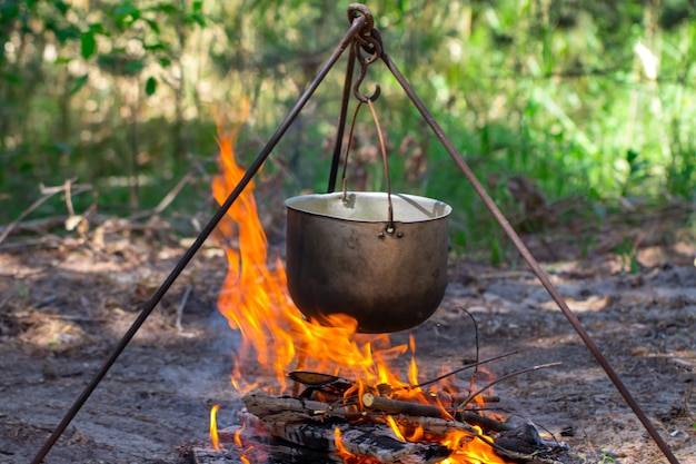 Toeristenpot die op een driepoot boven het vuur hangt. Koken in de campagne.