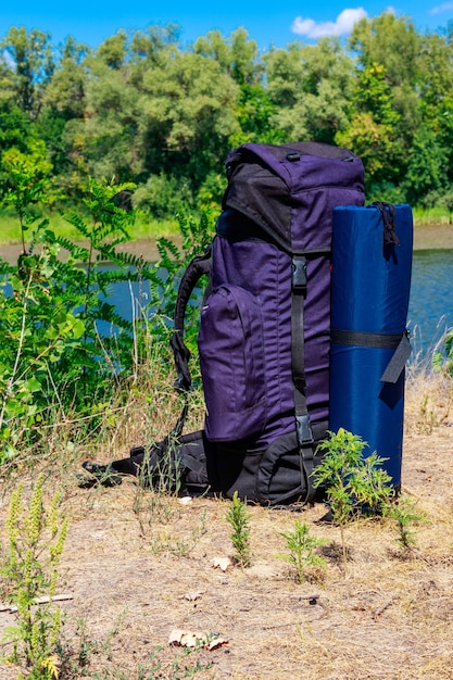 Toeristenrugzak dichtbij een rivier bij het concept van de zomerwandeling