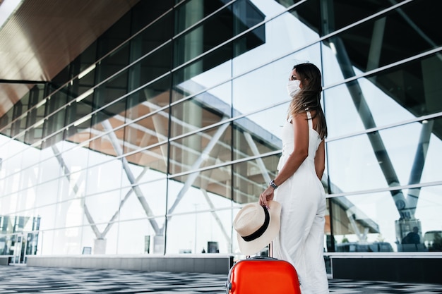 Foto toeristenvrouw in gekke masker die zich met bagage dichtbij luchthaven bevinden