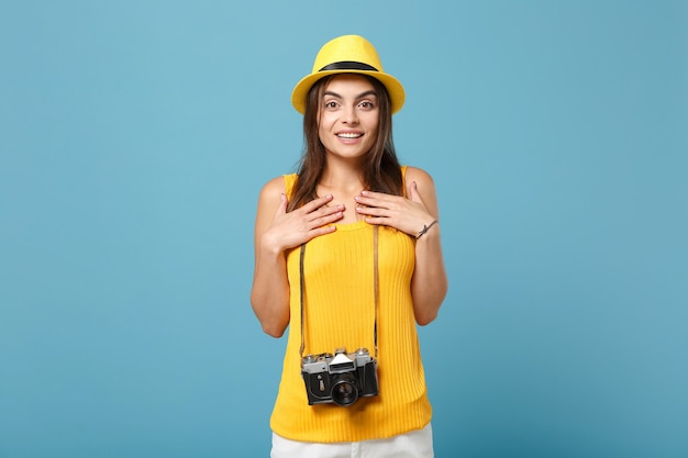 toeristenvrouw in gele zomerse vrijetijdskleding en hoed met fotocamera op blauw