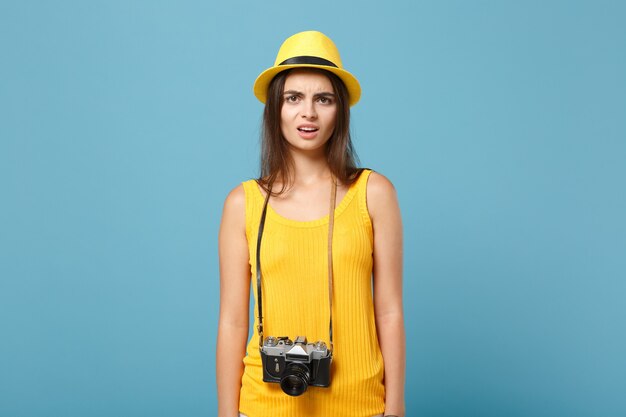 Toeristenvrouw in gele zomerse vrijetijdskleding en hoed met fotocamera op blauw