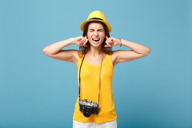 toeristenvrouw in gele zomerse vrijetijdskleding en hoed met fotocamera op blauw