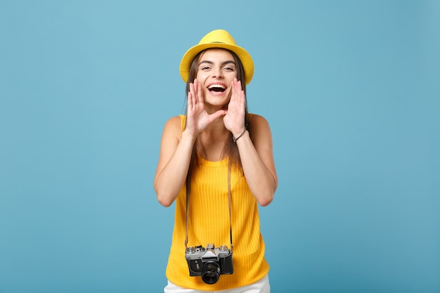 toeristenvrouw in gele zomerse vrijetijdskleding en hoed met fotocamera op blauw