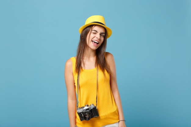 toeristenvrouw in gele zomerse vrijetijdskleding en hoed met fotocamera op blauw