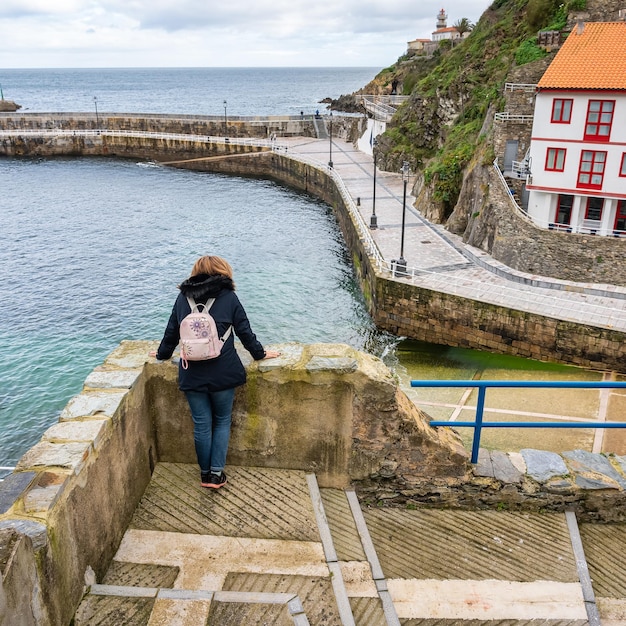 Toeristenvrouw leunt uit een straatbalkon en overweegt het uitzicht op het vissersdorp Cudillero Asturias