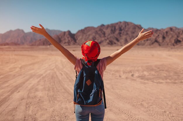 Toeristenvrouw met rugzak die sjaal op hoofd draagt Gelukkige reiziger die Sinai-woestijn en bergen bewondert met opgeheven handen Zomervakantie