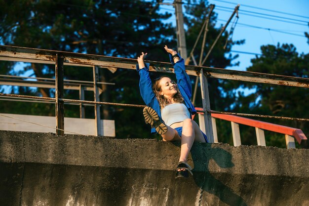 Toeristisch meisje geniet van het leven tijdens een wandeling in de buurt van de spoorlijn in de avond