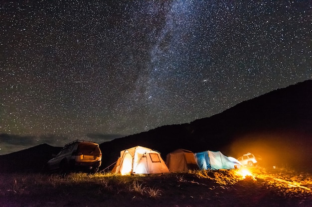 Toeristische camping aan de zeekust 's nachts onder de sterrenhemel. Er is wat ruis van hoge iso