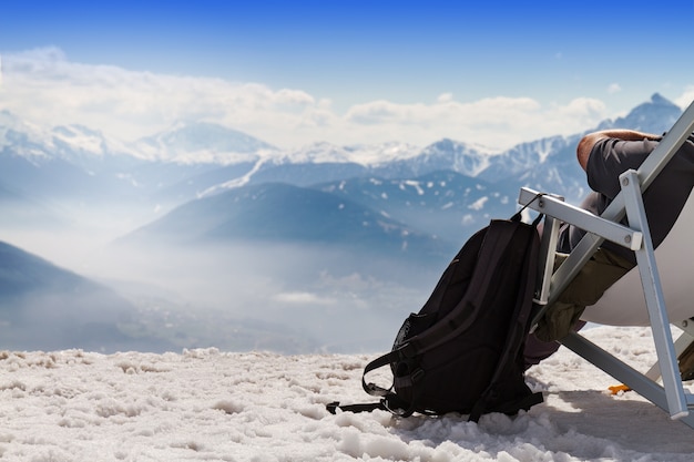 Toeristische chilling zitplaatsen in chaise-longue zonnebank op bergachtergrond, sneeuw. Horizontaal. Copy Space. Toerisme winterconcept.