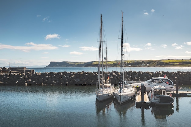 Toeristische jachten boot naast de kleine pier en stenen omheining Noord-Ierland comfortabele voertuigen