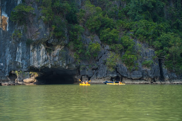 Toeristische jonken drijvend tussen kalksteenrotsen in Ha Long Bay mensen kajakken in een grot in Lan Ha Bay dicht bij Halong Bay Vietnam